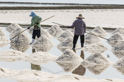 Farmers are using the tools to scoop the salt into a pile in salt garden at phetchaburi, thailand.