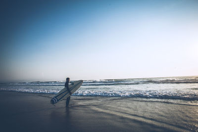 Man on beach against clear sky