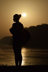 Silhouette man standing on beach against sky during sunset