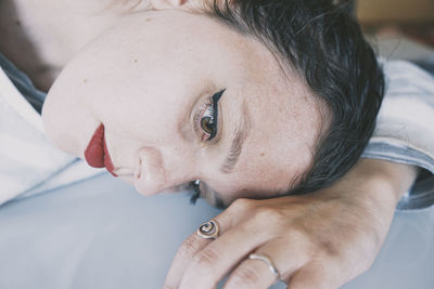 Close-up portrait of young woman lying on bed