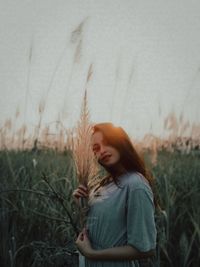 Woman looking away while standing on field against sky