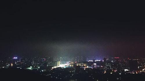 Illuminated cityscape against sky at night