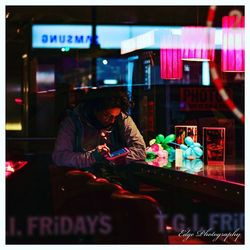 People sitting at illuminated market stall at night