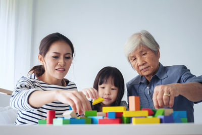 Family playing with toy blocks while sitting in home