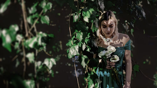 Portrait of woman standing against trees