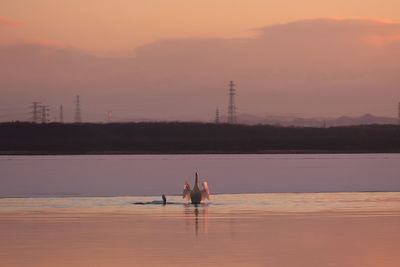 People sitting on boat against sky during sunset