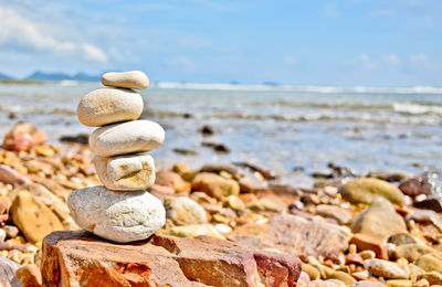 Stack of pebbles on beach against sky