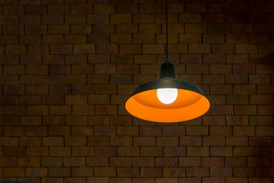 Low angle view of illuminated pendant light on wall