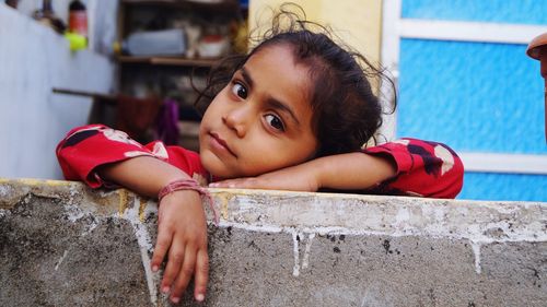 Portrait of smiling girl by retaining wall