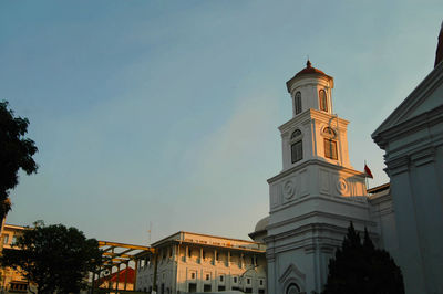 Low angle view of clock tower amidst buildings against sky