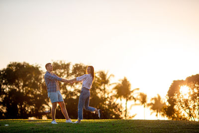 Low section of woman walking on field against sky during sunset
