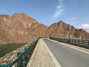 Empty road by mountain against sky