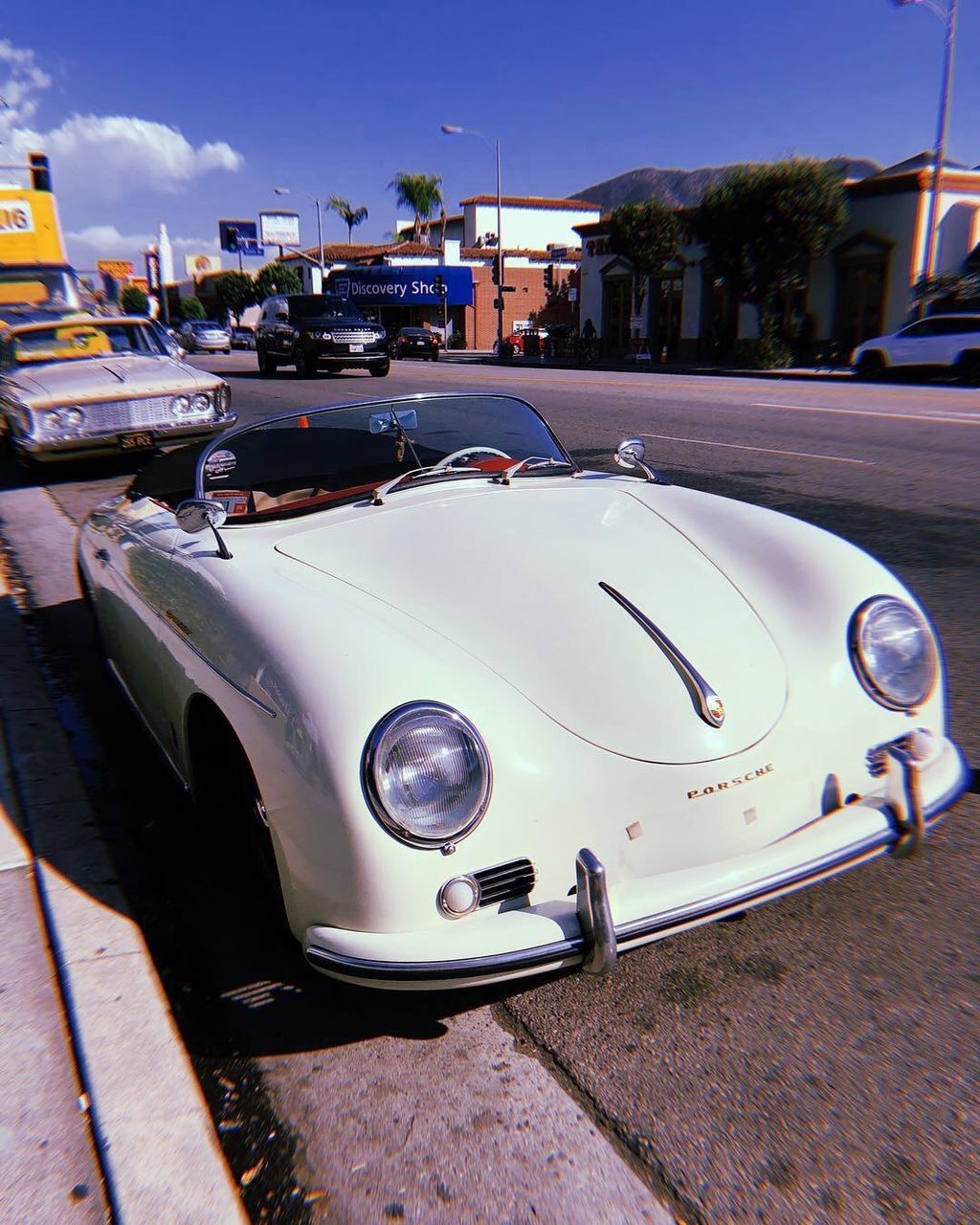 mode of transportation, car, transportation, motor vehicle, land vehicle, city, street, retro styled, vintage car, day, architecture, sky, headlight, no people, built structure, sunlight, building exterior, nature, road, outdoors, luxury