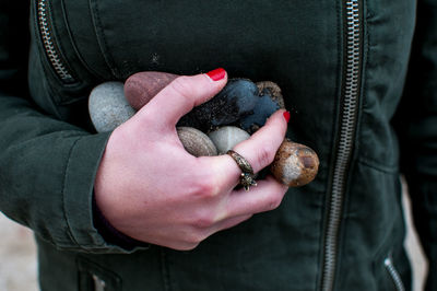 Midsection of woman holding pebbles