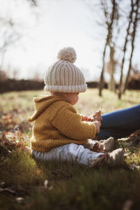 Mother and daughter wearing warm clothing while sitting on land