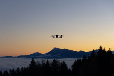 Low angle view of silhouette drone against sky during sunset