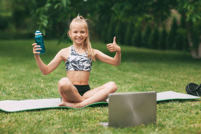 Portrait of smiling young woman using mobile phone in grass