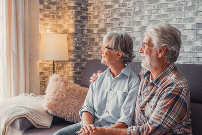 Side view of couple sitting on sofa at home