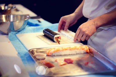 Midsection of chef preparing sushi in restaurant