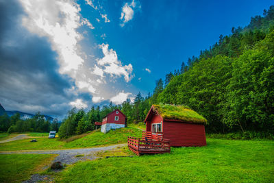 House amidst trees and plants on field against sky