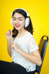 Smiling young woman against yellow wall