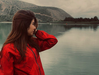 Young woman looking away against lake