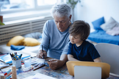 Senior man drawing on tablet pc by grandson at home