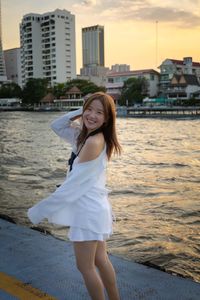 Portrait of young woman standing against river