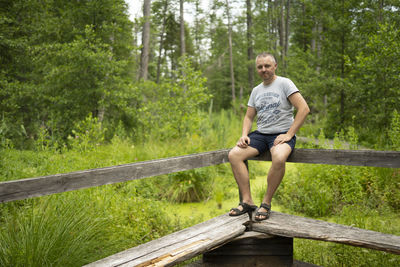 Portrait of smiling woman on footbridge in forest