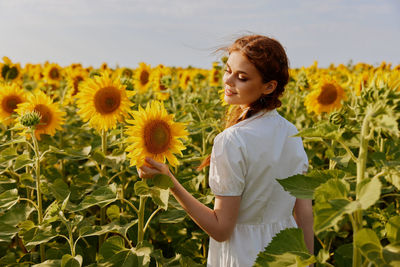 Woman standing on sunflower field