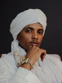 Portrait of young man with arms crossed against black background