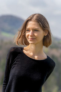 Portrait of young woman looking away against sea