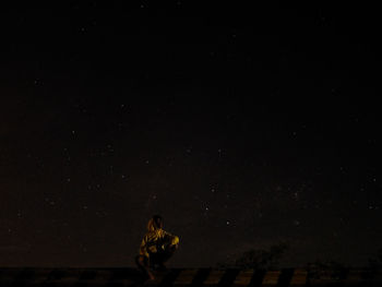 Woman standing against sky at night