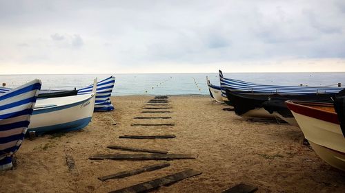 Deck chairs on beach against sky