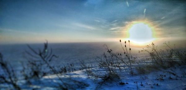Scenic view of frozen land against sky during sunset