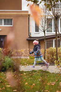 Full length of woman standing outside house against building