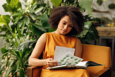 Young woman looking away while sitting on book