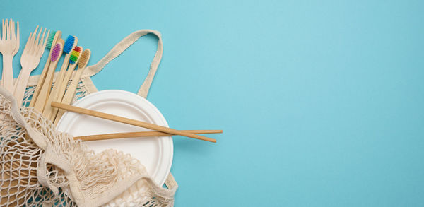 White textile bag and disposable tableware on a blue background. view from above, plastic rejection 