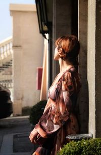 Woman looking up while standing against building