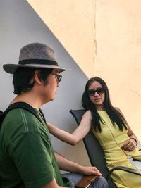 Young couple sitting against wall