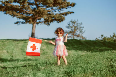 Girl with arms raised on field against sky