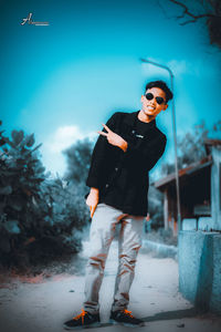 Young man wearing sunglasses standing against trees