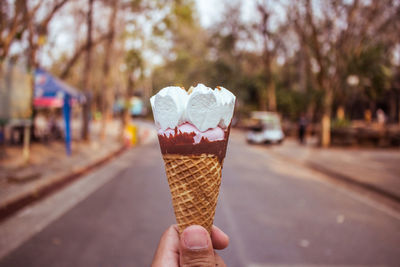 Cropped hand holding ice cream cone outdoors