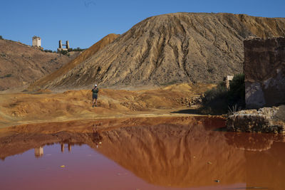 Man on rock by mountain against sky