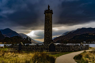 Tower amidst buildings against cloudy sky