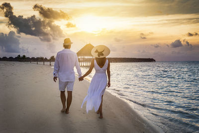 Rear view of couple walking on beach