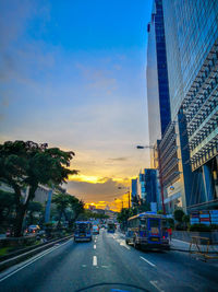 City street amidst buildings against sky during sunset