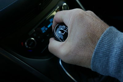 Cropped image of hand shifting gear in car