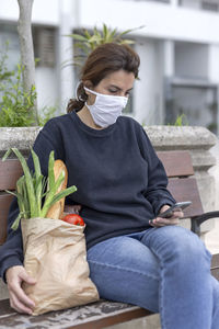 Midsection of woman holding while sitting outdoors