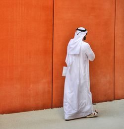 Rear view of woman standing against orange wall